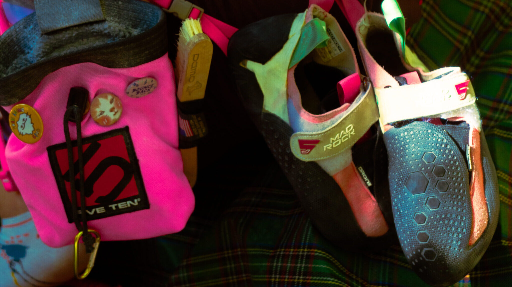 climbing shoes and chalk bag hanging from a woman's sport climbing harness